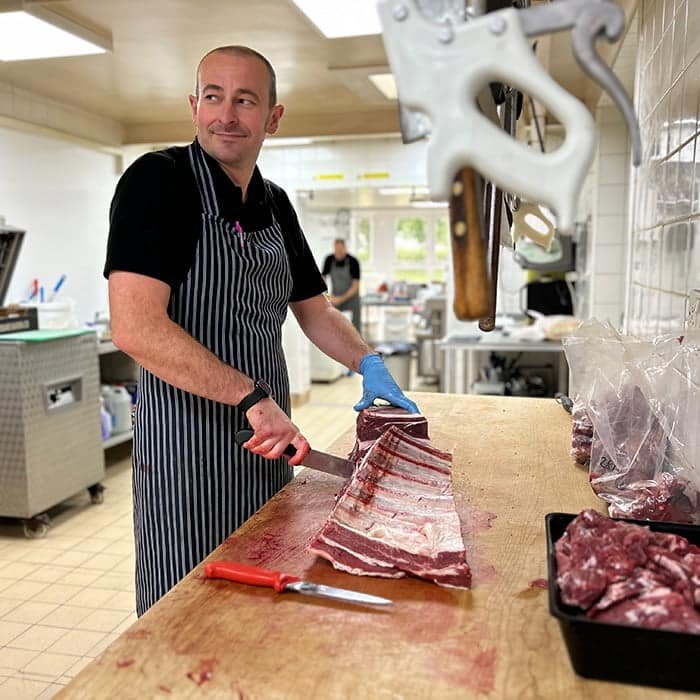 John Dawson cutting meat with Phillip Dawson in the backround at C Dawson & Sons